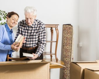 elderly couple packing up their books in cardboard boxes