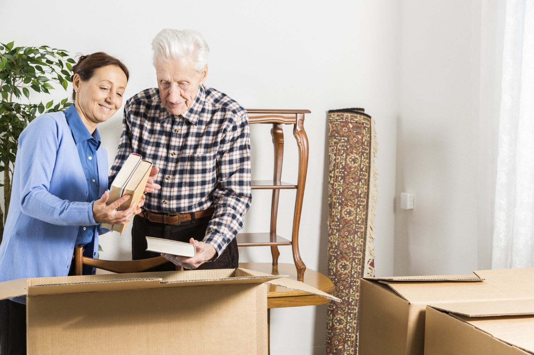 Elderly couple packing up their books in cardboard boxes.