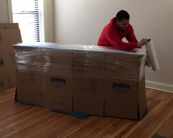 new city moving employee wrapping cardboard boxes with wrapping paper